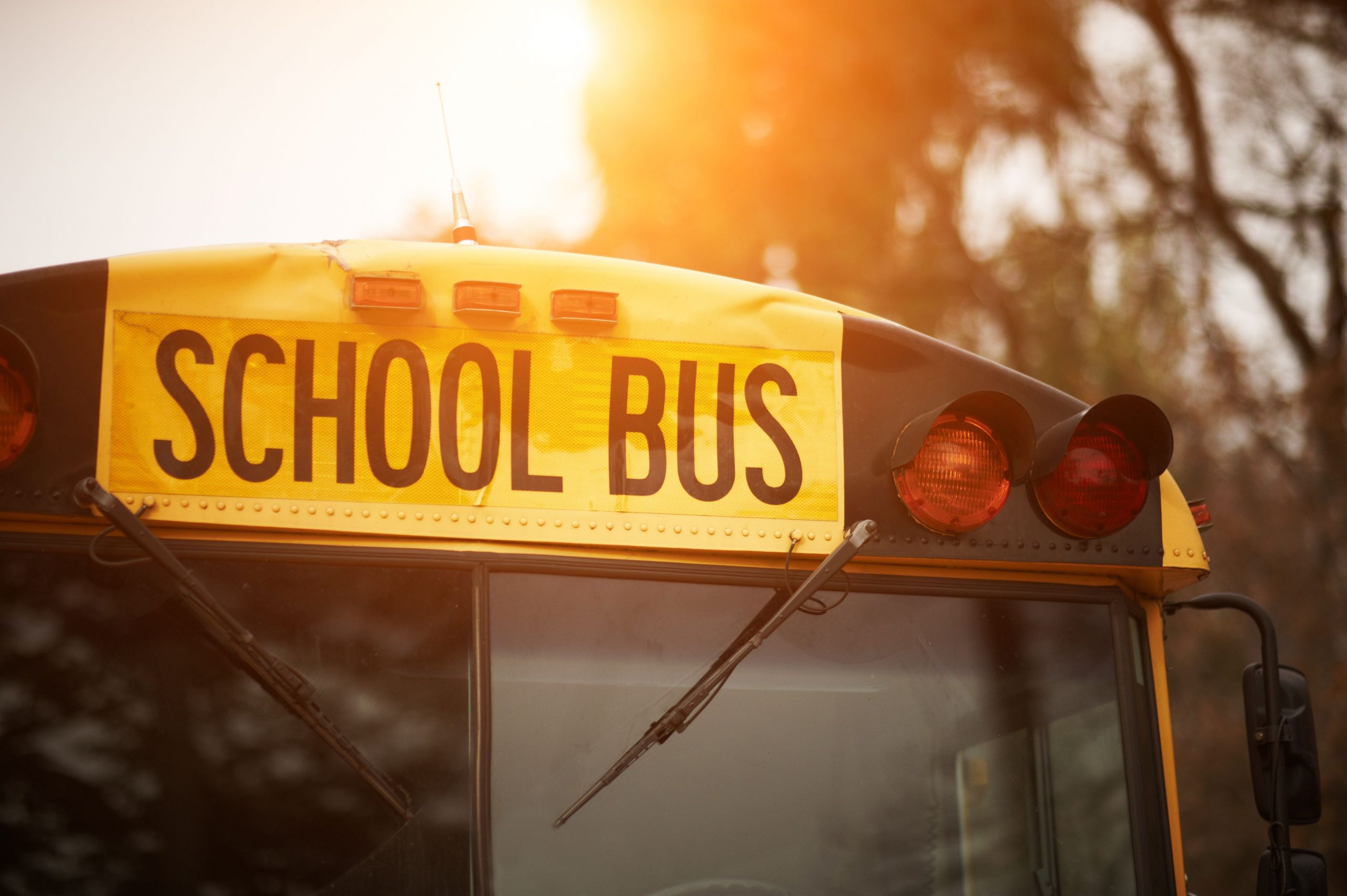 Front closeup view of yellow school bus windshield sign at sunset Front closeup view of yellow school bus windshield sign and lights at sunset