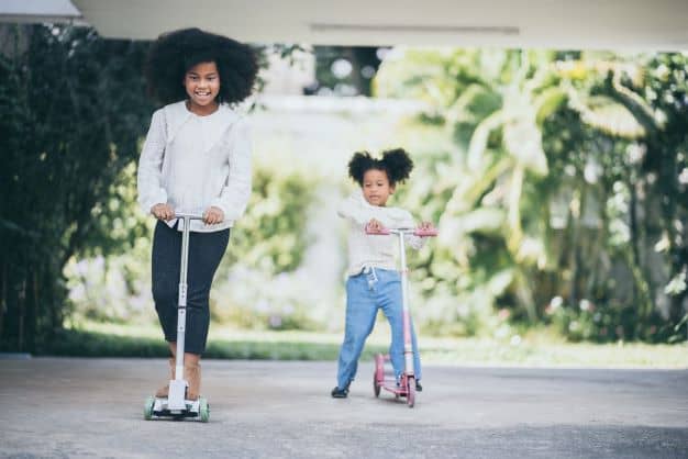 children riding a scooters on the street, kid playing together, afro African American children riding a scooters on the street, kid playing together, afro African American