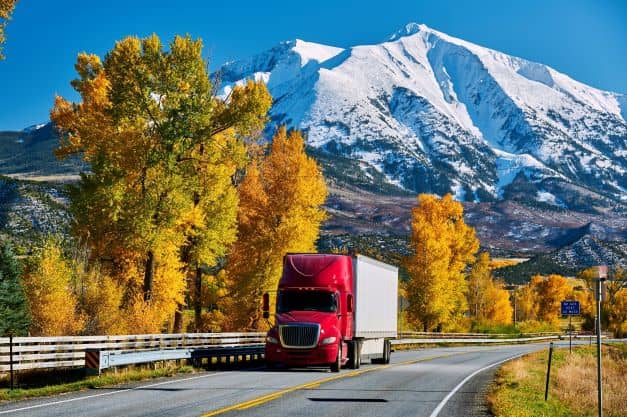 Red truck on highway in Colorado at autumn Red truck on highway in Colorado at autumn